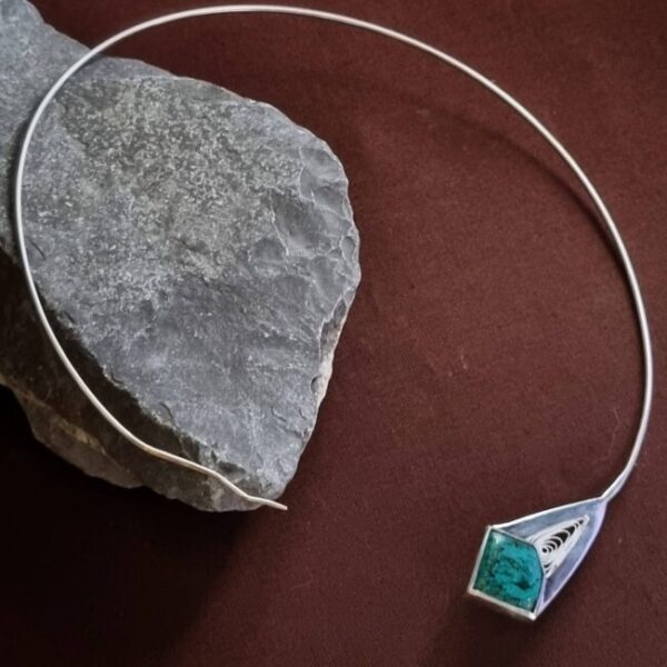 Tour de cou en argent serti d'une chrysocolle malachite posé sur une roche le tout sur fond marron