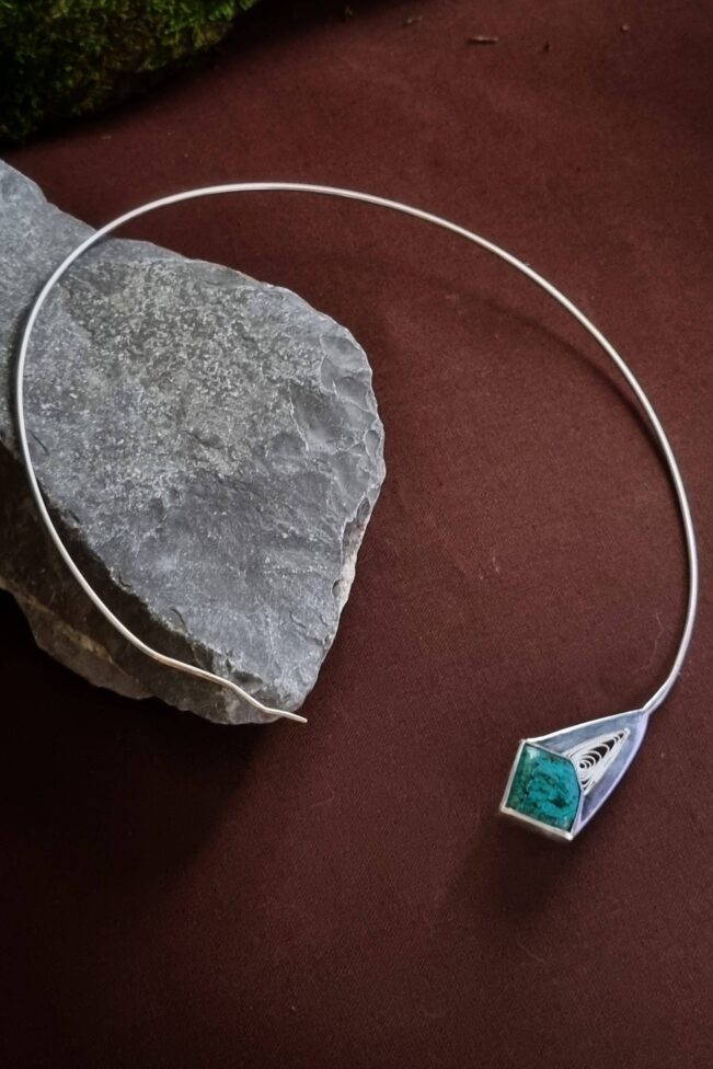 Tour de cou en argent serti d'une chrysocolle malachite posé sur une roche le tout sur fond marron