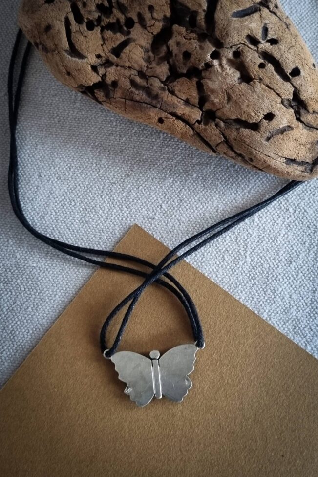 collier avec pendentif en argent papillon en filigrane sur un fond noirci