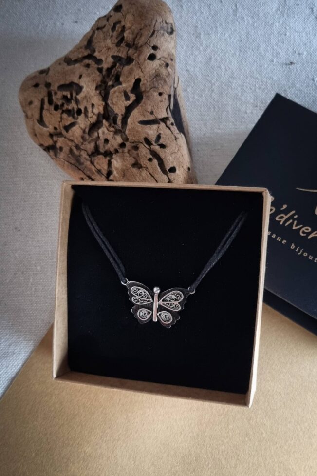 collier avec pendentif en argent papillon en filigrane sur un fond noirci