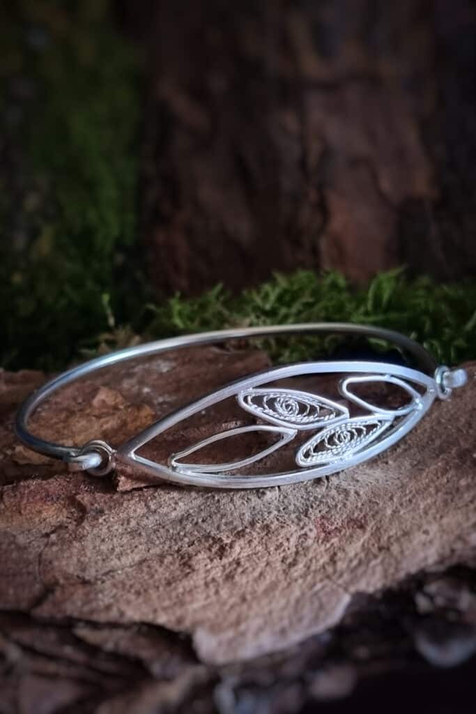 bracelet en argent avec filigrane, repr&eacute;sentant un brin d&rsquo;olivier, pos&eacute; sur une &eacute;corce