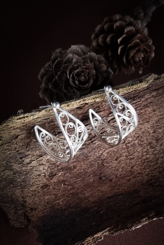 boucles d'oreilles en argent filigrané posées sur une écorce