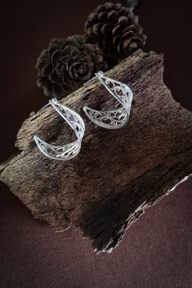 boucles d'oreilles en argent filigrané posées sur une écorce